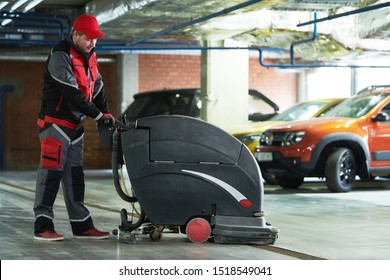 Worker With Machine Cleaning Floor In Parking Garage.