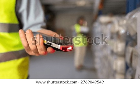 Worker makes checking inventory, scanning using handheld barcode scanner in industrial warehouse facility, closeup. Supply chain management, shipments in logistics center, stock information updates