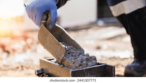 Worker making cube concrete casting by steel mould for control quality cement in building site.