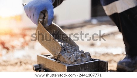 Worker making cube concrete casting by steel mould for control quality cement in building site.