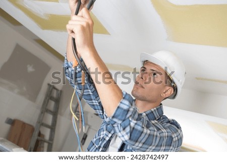 worker making mounting for an electric cable in ceiling