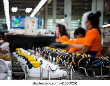 worker making sport shoe in footwear production line