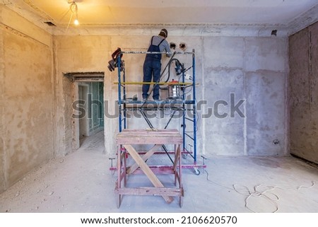 Worker is making a technological hole for electrical cabel in the wall in apartment that is under construction, remodeling, renovation, extension, restoration and reconstruction