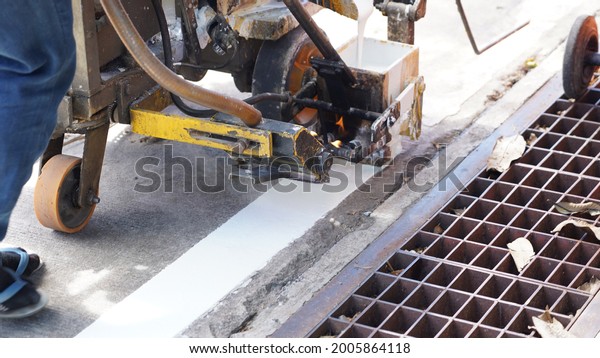 worker\
is making white road lane line on concrete\
road.