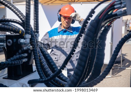 Worker man chek pipe system of hydraulic hose valves in industry machinery.