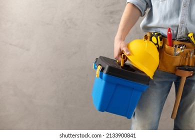 Worker man holding construction helmet tool and toolbox near concrete or cement wall. Male hand and hard hat for house room renovation. Home renovation concept