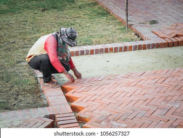 worker man install a charming herringbone-pattern brick walk. Building a Brick Walkway