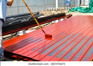 worker man paint rustproof with channels steel for building structure house roof. professional use equipment on iron surface.