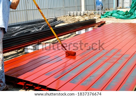 worker man paint rustproof with channels steel for building structure house roof. professional use equipment on iron surface.