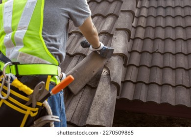Worker man replace tile of the old roof. Repair roof concept. - Shutterstock ID 2270509865