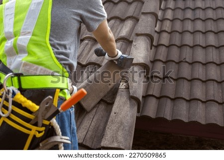 Worker man replace tile of the old roof. Repair roof concept.