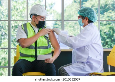 Worker Man Sitting To Getting Covid Vaccine, With Nurse Injecting Vaccine To Get Immunity For Protect Virus. Vaccination For Essential Workers In Clinic Healthcare At Industrial Factory.