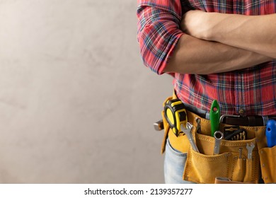 Worker man with tool belt near concrete or cement wall. Male hand and tools for house room renovation. Home renovation concept - Shutterstock ID 2139357277