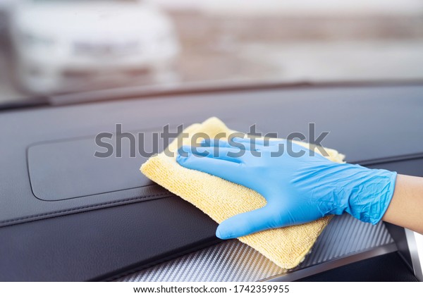 worker man wear gloves cleaning car interior\
console with microfiber cloth, detailing, car wash service concept.\
copy space.