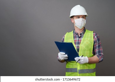 Worker Man Wearing Face Mask And Protective Hard Hat. Young Engineer Worker Wear A White Helmet And Medical Mask. Coronavirus Hygiene, Safety Concept