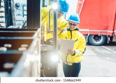 Worker And Manager At Distribution Center Behind A Forklift