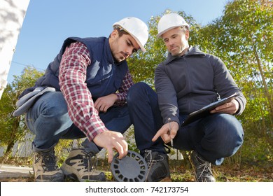 Worker And Manager Inspecting Sewer Drain