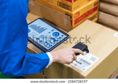 A worker manages package information using a handheld scanner and tablet.