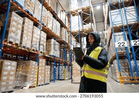 Worker managing logistics and inventory control with a tablet in a large cold chain storage warehouse