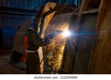 obrero con soldadura de mascarilla una pala excavadora en una fábrica