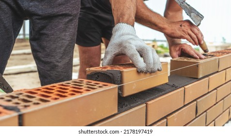 Worker or mason hands laying bricks close up. Bricklayer works at brick row. Brickwork on construction site