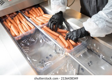 
A worker at a meat-packing plant for sausages. Sausages hang in a row. worker observes and checks, tests sausages. farm sausages are packaged