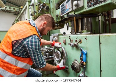 Worker In Metal Processing Factory Operates Drill Press On A Large Wheel