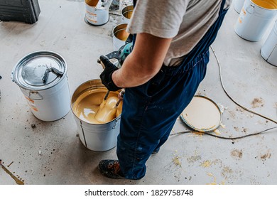 Worker Mixing Yellow Epoxy Resin With The Mixer In A Tin Bucket