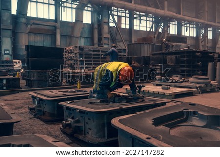 Worker with molds for metal cast in metallurgical plant foundry. Heavy industry