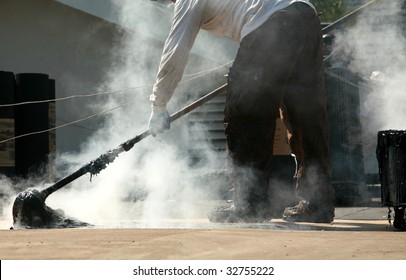 A Worker Mops Out Molten Tar On A Roof Replacement Job