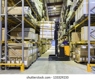 Worker In The Motion On Forklift In The Large Modern Warehouse