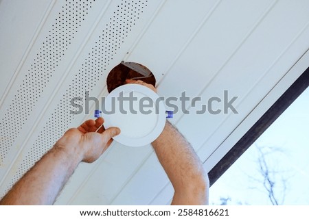 Worker mounting ceiling led light fixture while installing it in bright, contemporary soffit natural light.