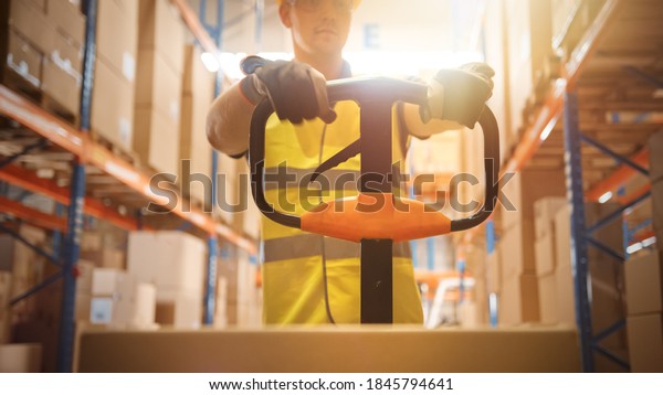 Worker\
Moves Cardboard Boxes using Hand Pallet Truck, Walking between Rows\
of Shelves with Goods in Retail Warehouse. People Work in Product\
Distribution Logistics Center. Point of View\
Shot
