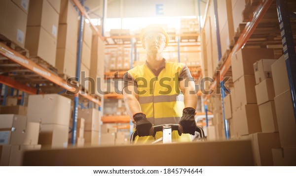 Worker Moves Cardboard Boxes using Hand Pallet\
Truck, Walking between Rows of Shelves with Goods in Retail\
Warehouse. People Work in Product Distribution Logistics Center.\
Point of View Sunflare\
Shot
