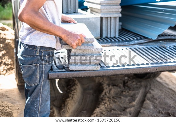 Worker moving heavy building materials from\
trunk car pickup.  Construction male worker carry loading concrete\
block for house\
construction.
