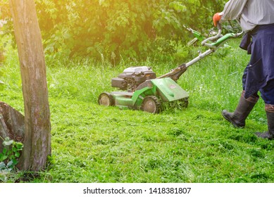 Worker mows the grass on the lawn in the park gasoline lawn mower. - Shutterstock ID 1418381807