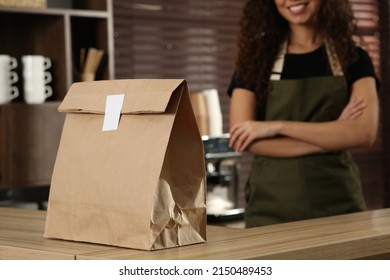 Worker Near Counter In Cafe, Focus On Paper Bag