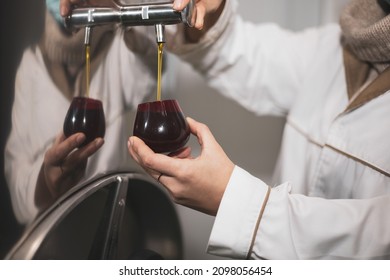 A worker obtains a small sample of virgin olive oil for a tasting in an oil mill. - Powered by Shutterstock