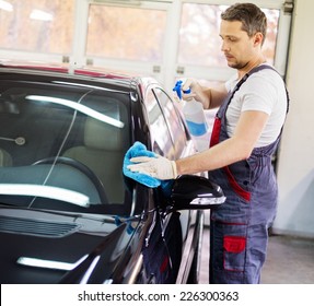 Worker On A Car Wash Cleaning Car With A Spray