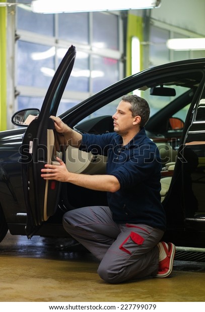 Worker on a car wash\
cleaning car interior 