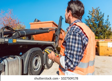 Worker On Construction Site Unloading Container For Waste From Truck Using Remote Control 