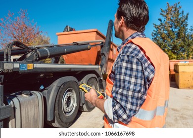 Worker On Construction Site Unloading Container For Waste From Truck Using Remote Control 