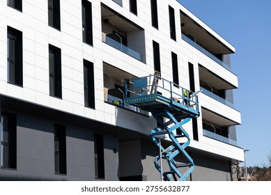worker on an elevated platform installing panels on a contemporary apartment building