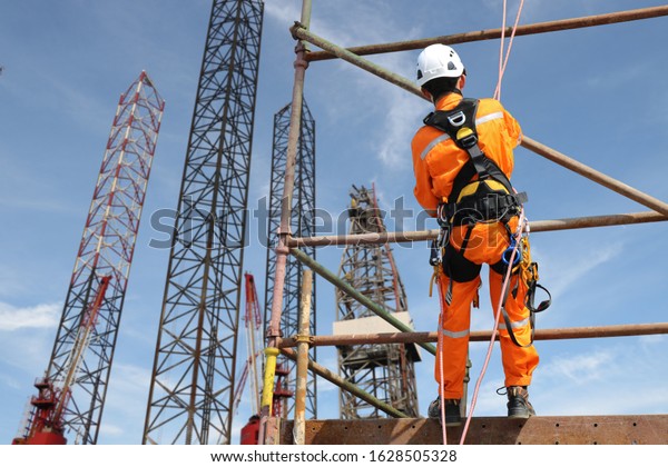worker on high on scaffolding wearing safety\
harness, Rope access and abseiling worker on high wear dresses for\
safety concept.