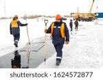 Worker on the ice of a frozen lake with bogr in his hand on ice mining