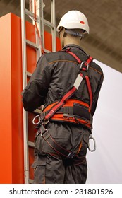 Worker On A Ladder Uses A Safety Harness To Prevent Falling From The Building