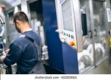 Worker on robotic line for bottling pure spring water. Selective focus on red button and short depth of field.