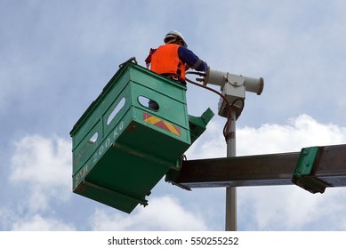 A Worker On A Sky Lift Doing Maintenance Work On An Explosive Proof Security Camera.