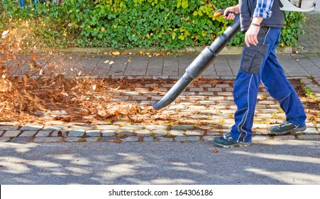 Worker On A Street In Autumn With A Leaf Blower