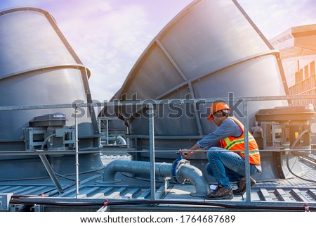 worker open valve of cooling tower on blue sky background. worker opening butterfly valve on top of cooling Tower. worker check valve on cooling tower.
